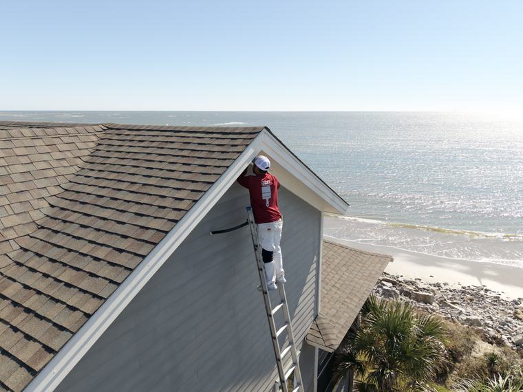 Reflections painter on a ladder painting an oceanfront home in Charleston